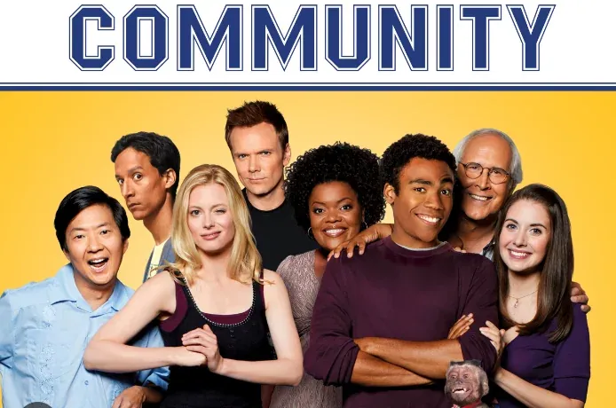 The cast of Community posed together against a yellow background under the blue show logo.
